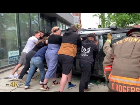 Canada: Bystanders help firefighters holding a car upright during...